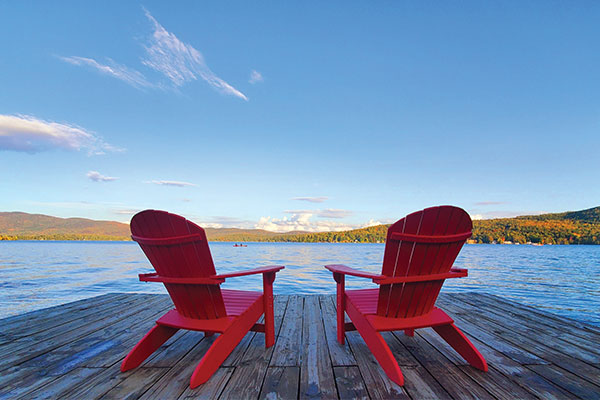 Two red ADK chairs overlooking lake. Photo credits: Lindsay DiGirolamo