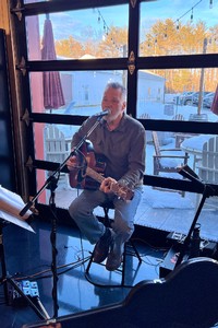 Chuck Kelsey singing and playing guitar